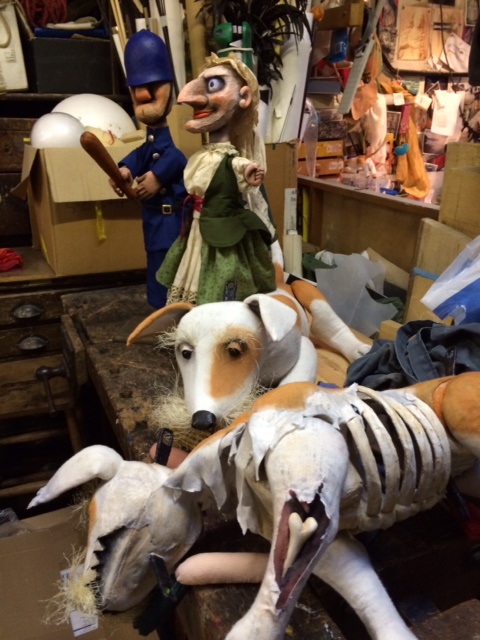 Puppets and a model of a skeletal animal on a workbench in a puppet workshop.