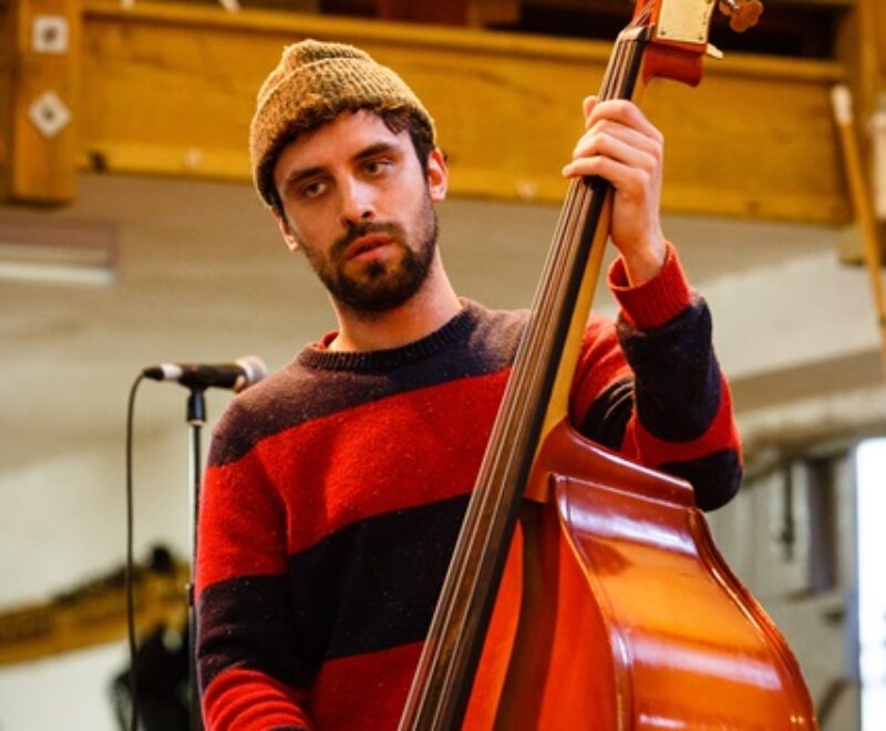 Man playing a double bass indoors.