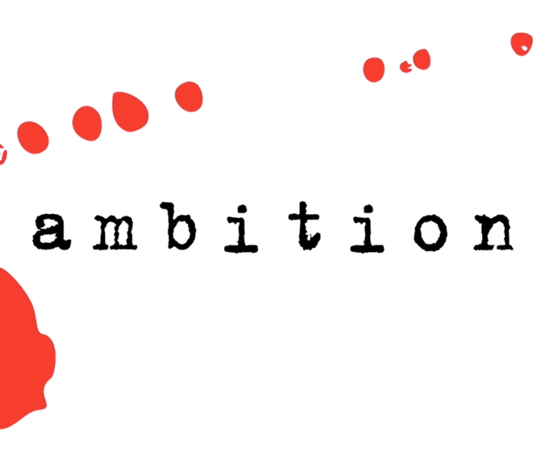 The word 'ambition' in lowercase black typewriter style font is centered in the image. A red mark, as if a splash of ink,