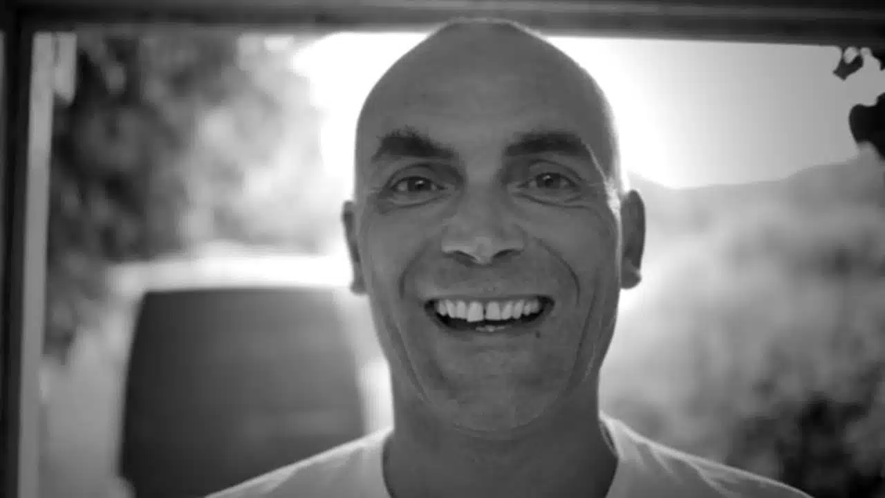Black and white portrait of a bald man smiling at the camera.