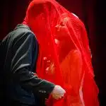 Tristan & Yseult stood together under the red veil, about to kiss