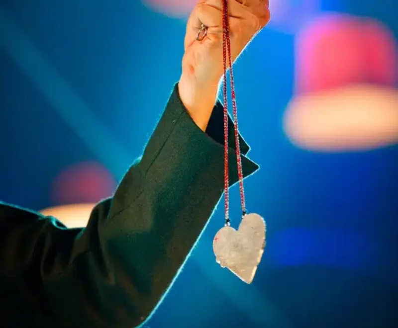 Close up image of a heart on a necklace held by Tristan