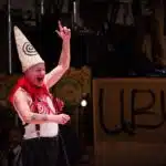 Photograph from Kneehigh's Ubu. Performance photograph of Mike Shepherd in full costume and make up with black, white and red costume.