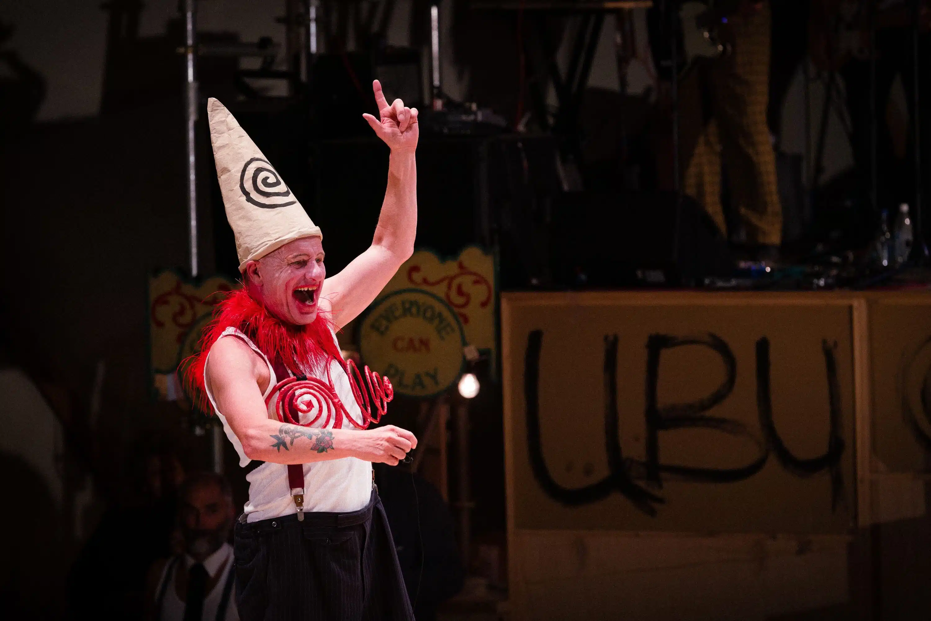 Photograph from Kneehigh's Ubu. performance photograph of Mike Shepherd in full costume and make up with black, white and red costume.